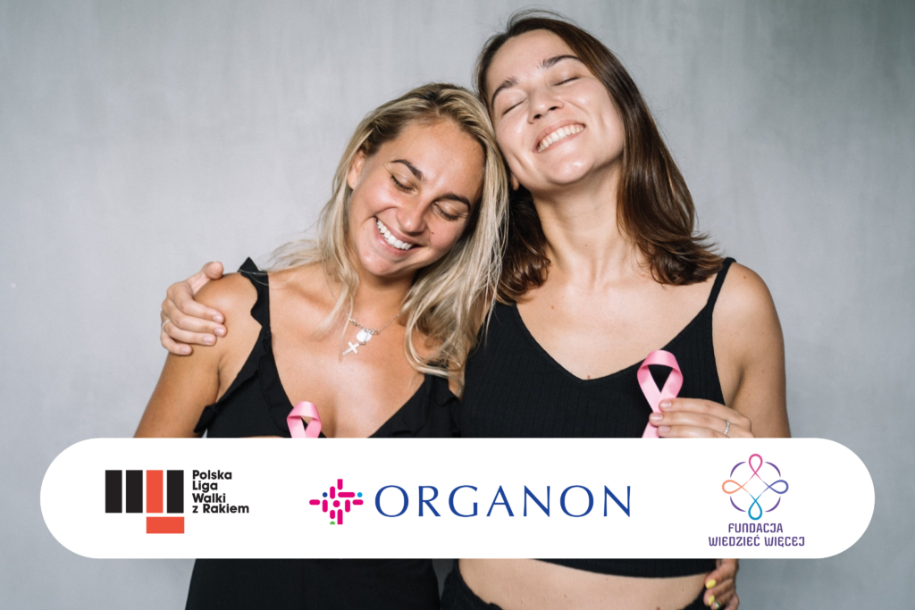 Dwie uśmiechnięte kobiety w czarnych topach trzymają w dłoniach różowe wstążki - symbol walki z rakiem piersi